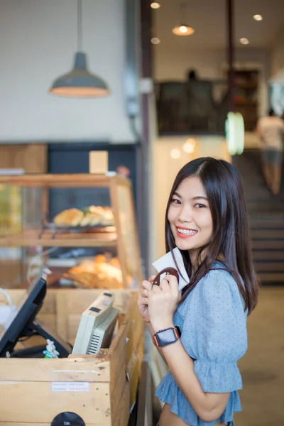 Young asian woman ordering coffee at the counter in a cafe business women in cafe