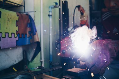 Çelik kaynak fabrikalarındaki fabrika atölyesinde kaynak yapan işçi eli.