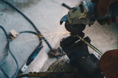 Mekanik adam, metal endüstrisinde alev kıvılcımları saçan elektrikli öğütücü kullanıyor.