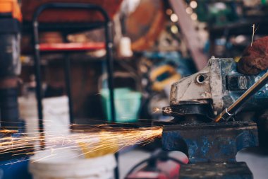 Mekanik adam, metal endüstrisinde alev kıvılcımları saçan elektrikli öğütücü kullanıyor.