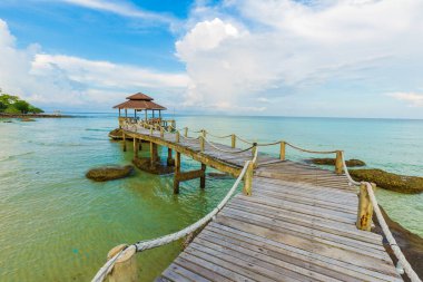 Tahta bir köprü ile deniz kıyısına ahşap kulübe mavi gökyüzü manzarası