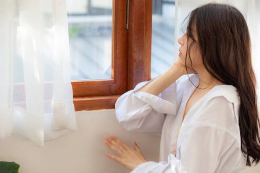 Mutlu güzel bir kadın pencereyi açıyor. Sabah yatak odasında uyanıyor.