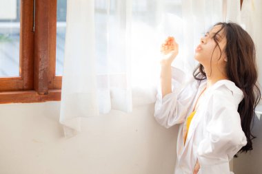 Mutlu güzel bir kadın pencereyi açıyor. Sabah yatak odasında uyanıyor.