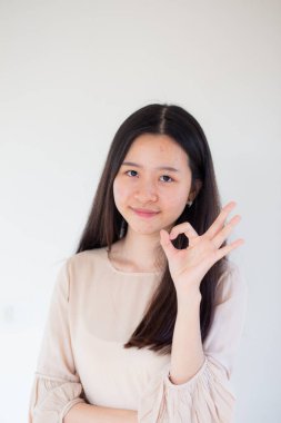 Beyaz arka planda duran mutlu, genç bir kadın iyi bir jest yapıyor. Kadınlar Tamam Parmak İmza