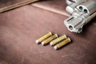 .44 magnum koli tabancası. Deri arka plandaki kişisel silahta kurşun var.