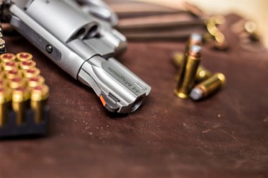 .44 magnum koli tabancası. Deri arka plandaki kişisel silahta kurşun var.