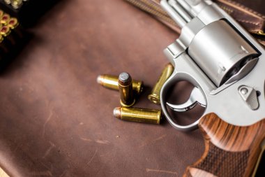 .44 magnum koli tabancası. Deri arka plandaki kişisel silahta kurşun var.
