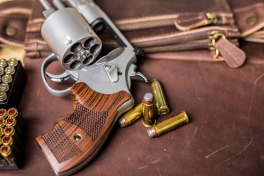 .44 magnum koli tabancası. Deri arka plandaki kişisel silahta kurşun var.