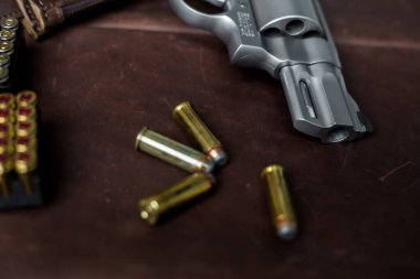 .44 magnum koli tabancası. Deri arka plandaki kişisel silahta kurşun var.