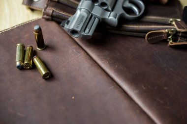 .44 magnum koli tabancası. Deri arka plandaki kişisel silahta kurşun var.