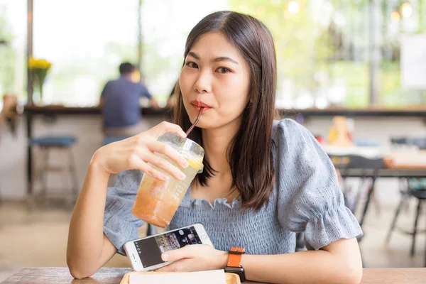 現代のカフェに座っているアジアの女性アイスレモンソーダぼやけた人々の背景 — ストック写真
