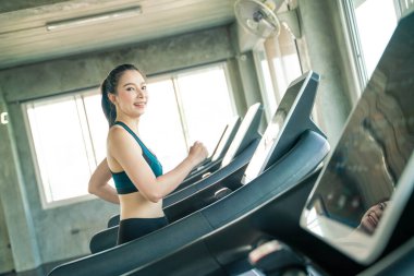 Koşu bandında koşan Asyalı kadın spor salonunda, kardiyo egzersizinde.