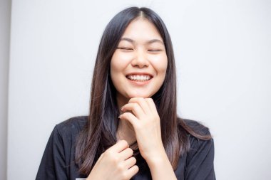 Genç, güzel Asyalı kadın beyaz arka planda siyah tişörtle poz veriyor.