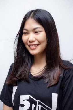 Genç, güzel Asyalı kadın beyaz arka planda siyah tişörtle poz veriyor.