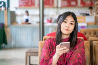 Güzel Asyalı kadınlar akıllı telefondan mesaj yolluyor kahve dükkanında oturuyor iş iletişimi konsepti