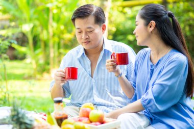 Yaşlı bir emekli çift parkta oturmuş, aşk konsepti ümidiyle ahşap bankta konuşuyor.