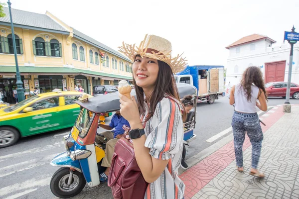 Beautiful women eat ice cream while travel in urban city lifestyle walking on downtown street of Bangkok City, Thailand, Concept Travel