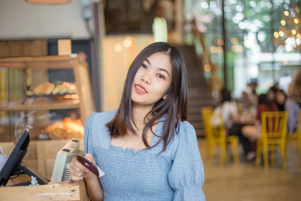 Young asian woman ordering coffee at the counter in a cafe business women in cafe