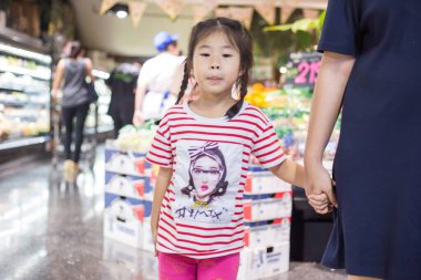 Güzel genç anne ve küçük kızı süpermarkette yürüyorlar, anne ve kız süpermarkette alışveriş yapıyorlar.