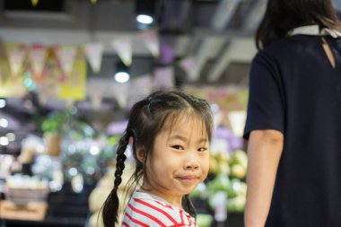 Güzel genç anne ve küçük kızı süpermarkette yürüyorlar, anne ve kız süpermarkette alışveriş yapıyorlar.