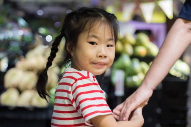 Güzel genç anne ve küçük kızı süpermarkette yürüyorlar, anne ve kız süpermarkette alışveriş yapıyorlar.