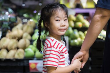 Güzel genç anne ve küçük kızı süpermarkette yürüyorlar, anne ve kız süpermarkette alışveriş yapıyorlar.