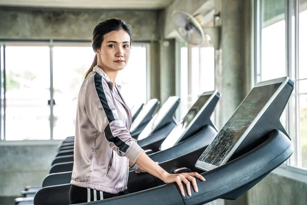 在健美运动馆健康的生活方式中微笑着跑在跑步机上的亚洲女人 — 图库照片
