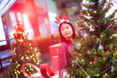 Kıvırcık saçlı oldukça çekici Asyalı bir kadın Noel süslemeleri takıp gece yeni yılı kutluyor.