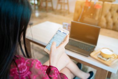 Güzel Asyalı kadınlar akıllı telefondan mesaj yolluyor kahve dükkanında oturuyor iş iletişimi konsepti