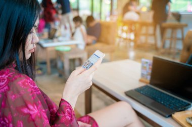 Güzel Asyalı kadınlar akıllı telefondan mesaj yolluyor kahve dükkanında oturuyor iş iletişimi konsepti