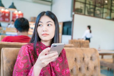 Güzel Asyalı kadınlar akıllı telefondan mesaj yolluyor kahve dükkanında oturuyor iş iletişimi konsepti