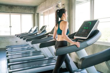 Koşu bandında koşan Asyalı kadın spor salonunda, kardiyo egzersizinde.