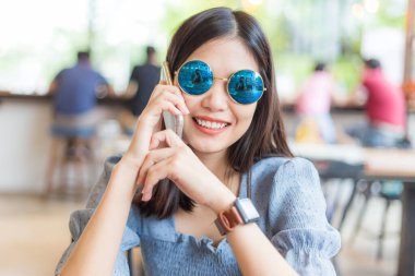 Kafede oturan Asyalı iş kadınları akıllı telefon iletişim sosyal camiası kullanıyor