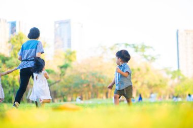 Küçük çocuk şehir parkında çimde koşuyor. Gün batımı zamanı. Ağaç dinlenme haftasonu.