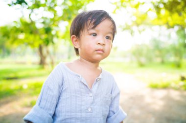 Küçük çocuk şehir parkında yürüyor ve ağaç doğası öğreniyor.