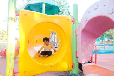 Gülümse mutlu Asyalı çocuk renkli çocuk parkında oynuyor anaokulunda.