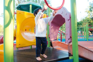 Gülümse mutlu Asyalı çocuk renkli çocuk parkında oynuyor anaokulunda.