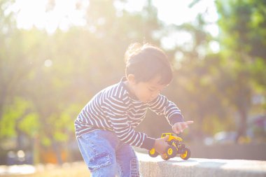 Parktaki yeşil çimlerde oynayan küçük çocuk. Doğadaki gündoğumu çocuğu.