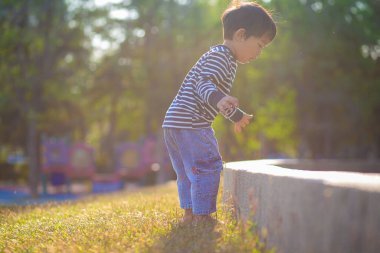 Parktaki yeşil çimlerde oynayan küçük çocuk. Doğadaki gündoğumu çocuğu.