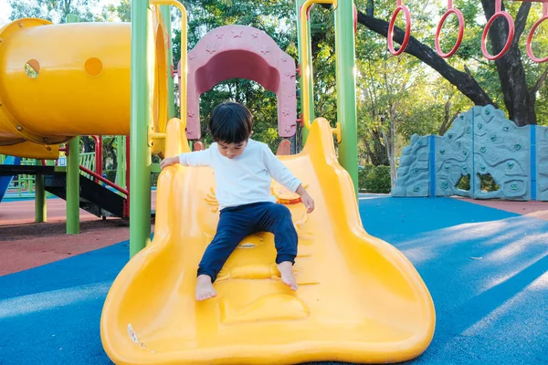 Gülümse mutlu Asyalı çocuk renkli çocuk parkında oynuyor anaokulunda.