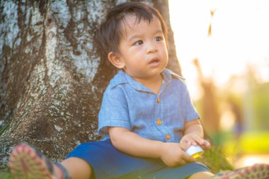 Yeşil çimlerde oynayan sevimli Asyalı çocuk. Şehir parkında gün batımı. Doğa eğlencesi.