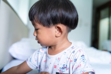 Küçük çocuk sabah yatağında uyur beyaz battaniyeyle uyanır.