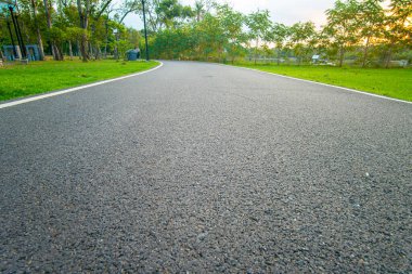 Yeşil şehir parkında asfalt yürüyüş ve koşu yolu gün batımı doğa eğlencesi