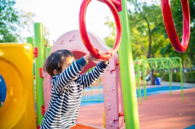 Asyalı bir çocuk doğadaki halk parkında çocuk parkına tırmanıyor.