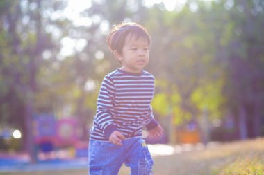 Sabahleyin yeşil çimlerde koşan sevimli küçük çocuk parkın güneş doğuşu egzersizi