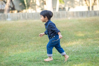 Sabahleyin yeşil çimlerde koşan sevimli küçük çocuk parkın güneş doğuşu egzersizi