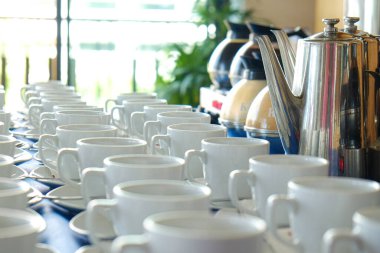 Kahve fincanı sehpanın üzerinde kavanozdan kahve dökülüyor.