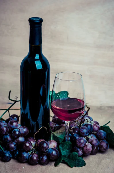 Bottiglie di vino con vetro e uva rossa, fondo in legno — Foto Stock