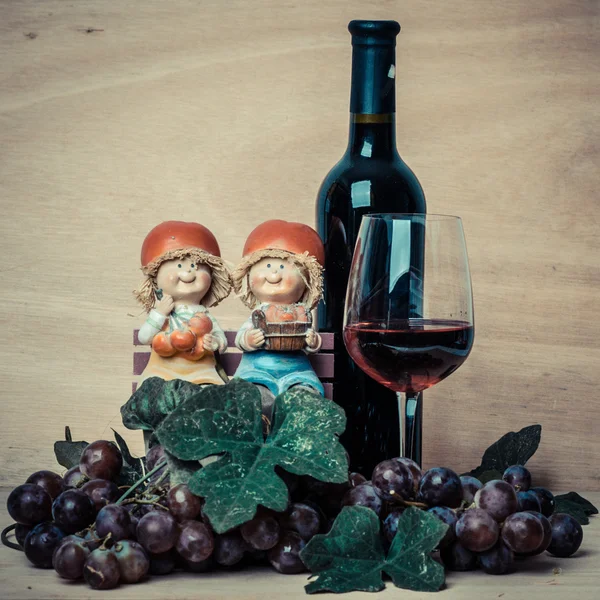 Garrafa de vinho tinto e uvas sobre fundo de madeira — Fotografia de Stock