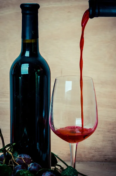 Наливание красного вина в бокал вина на деревянном фоне — стоковое фото